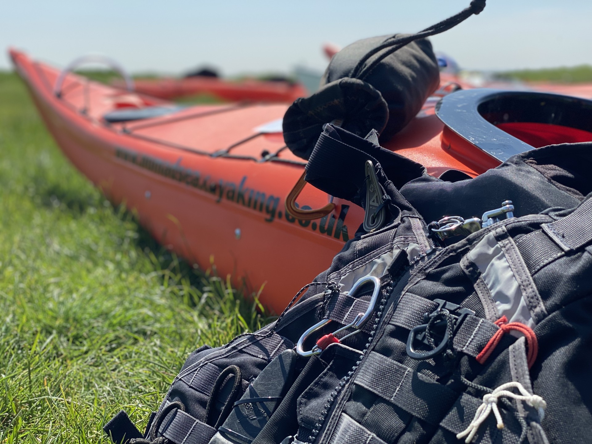 Black buoyancy aid next to a red sea kayak.