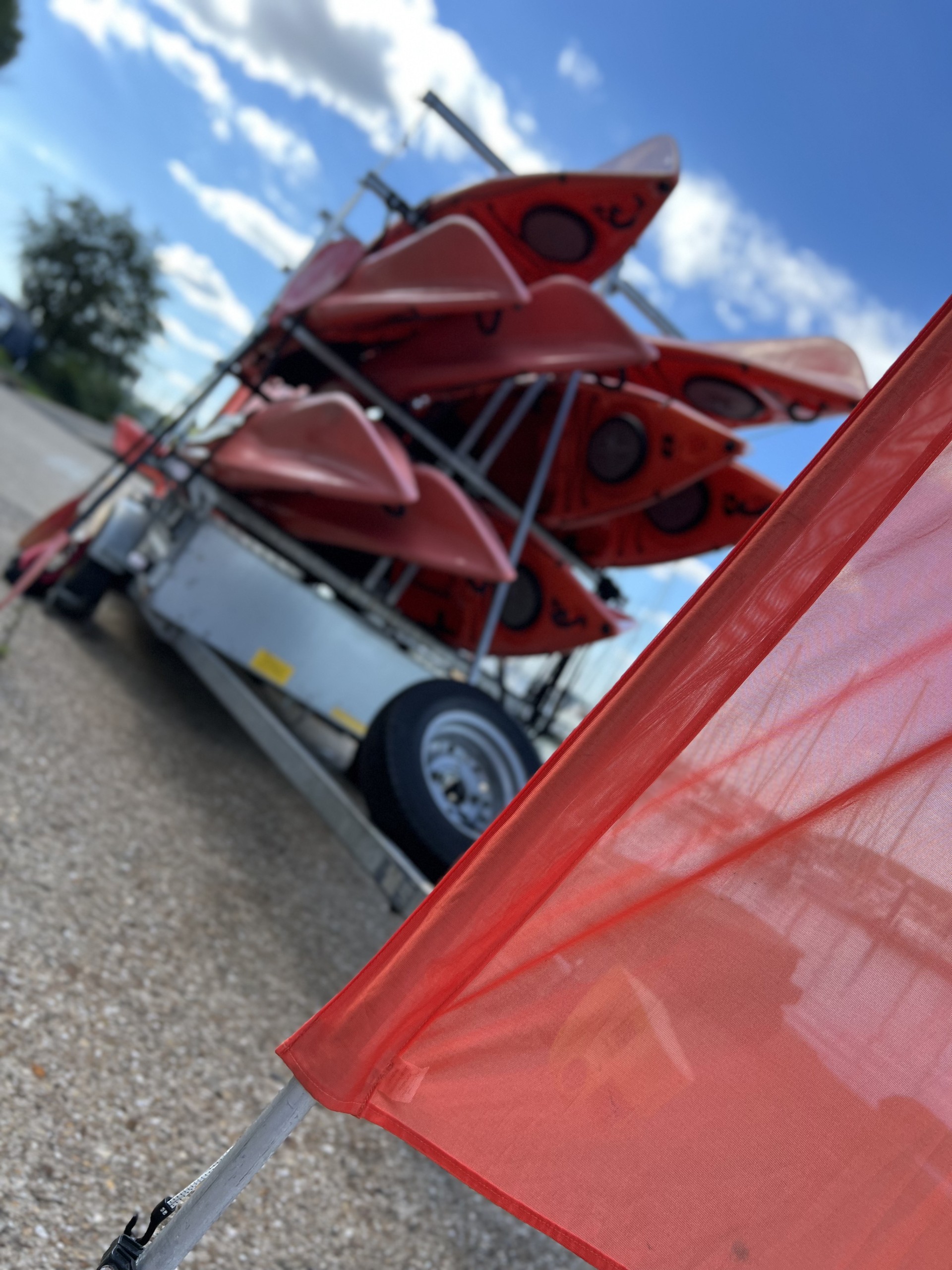 Orange sit-on-tops loaded on a trailer with NOMAD Sea Kayaking.